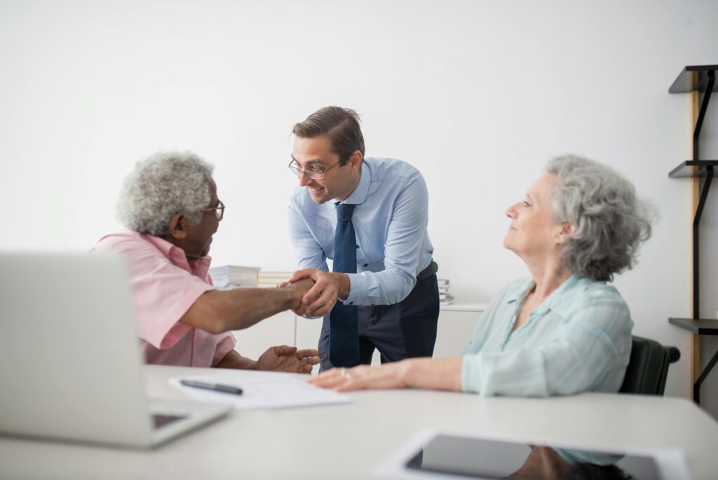 Business professional meeting with senior clients in an office setting, showcasing diversity and cooperation.